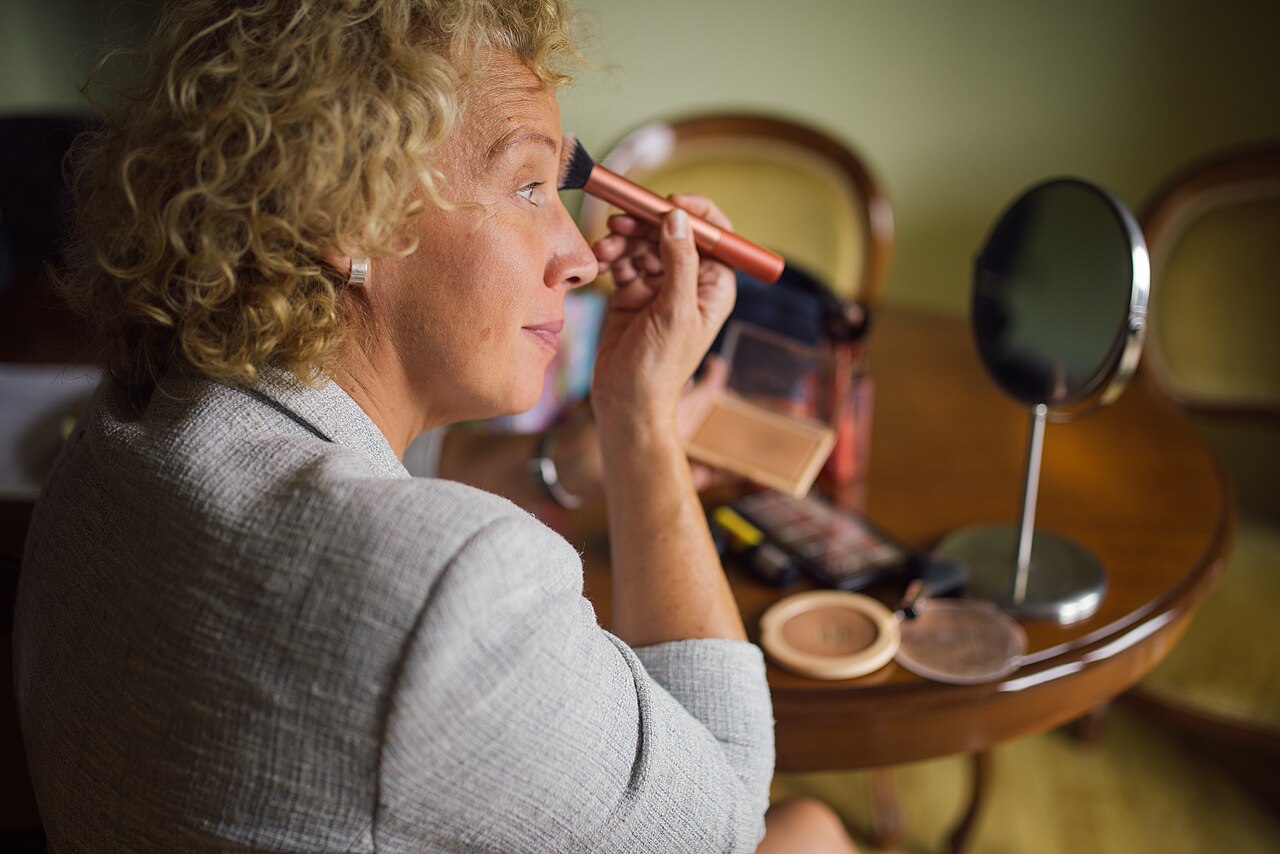 A woman applying makeup in front of a mirror