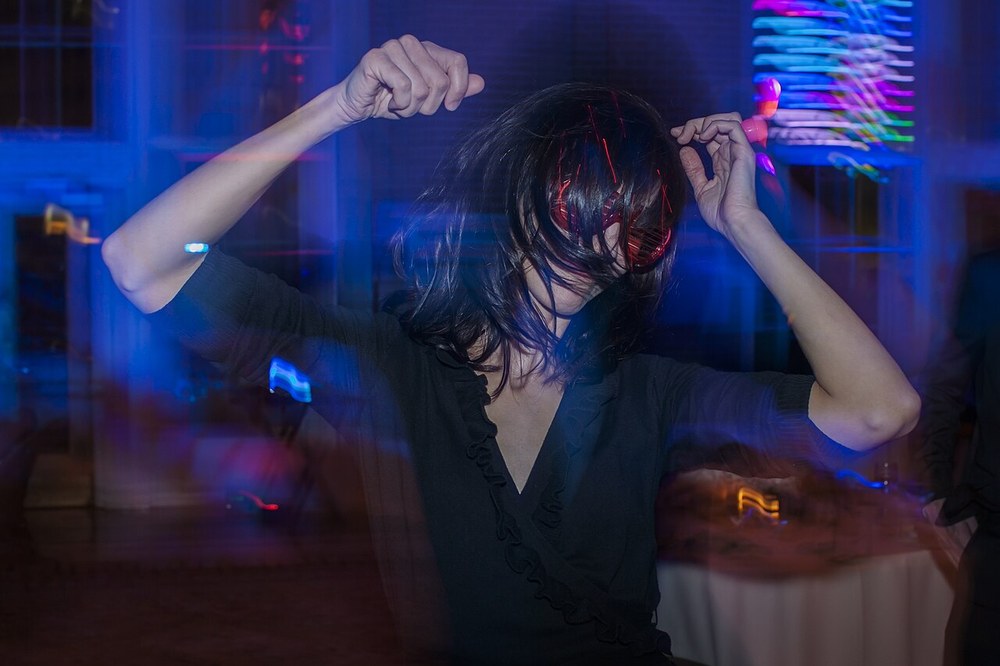 A woman dancing at a party under coloured lights
